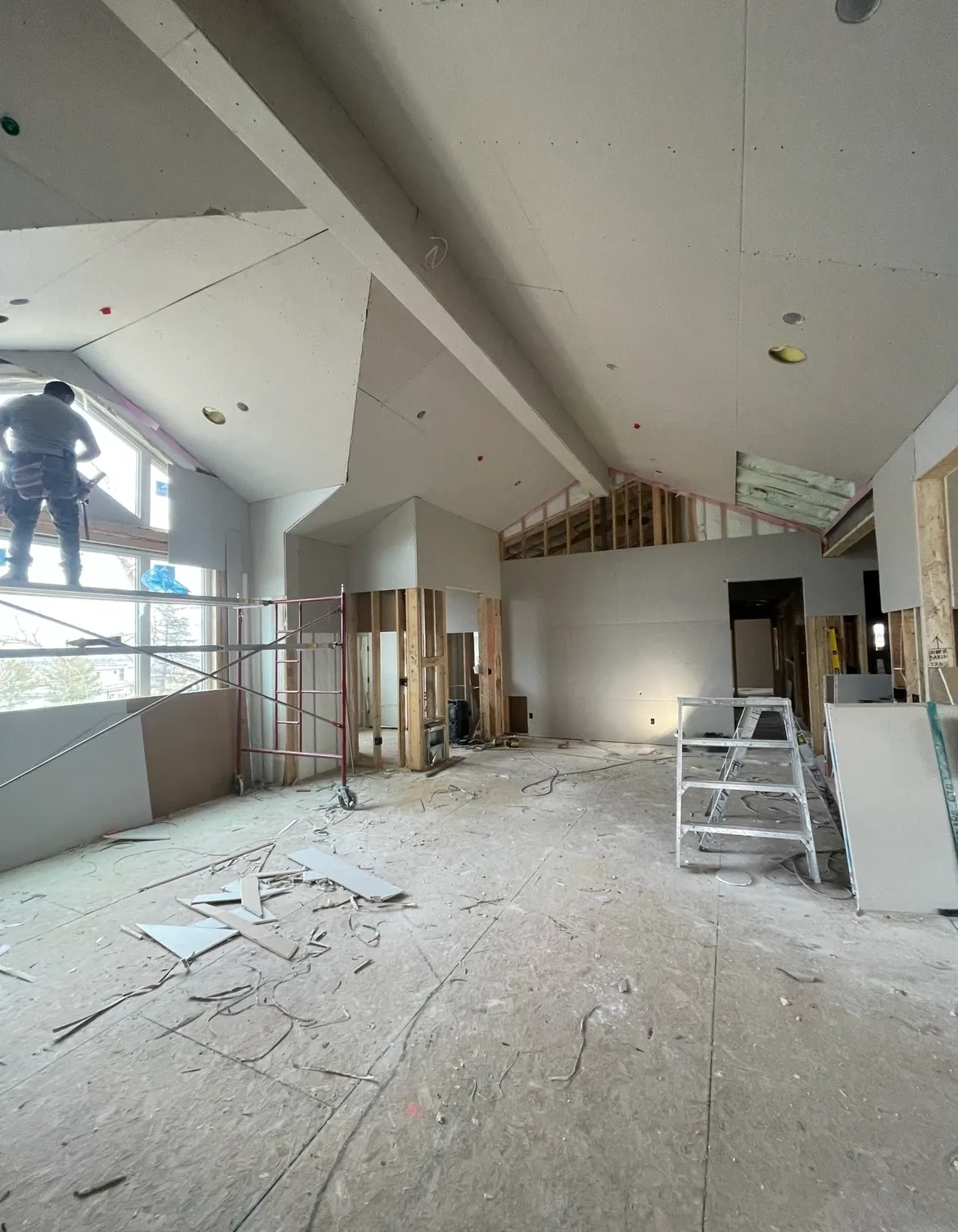 A man standing on a ladder in a room under construction