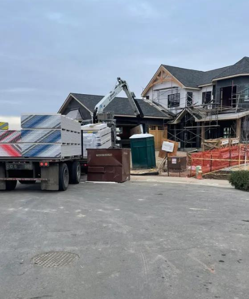 A dump truck parked in front of a house under construction